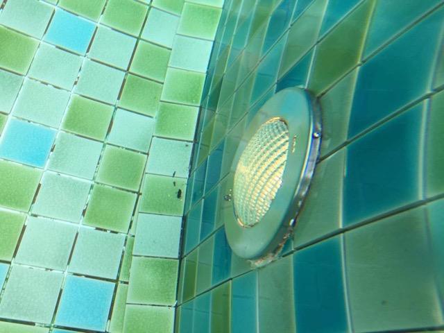 Technician replacing underwater pool light in villa pool on Koh Samui